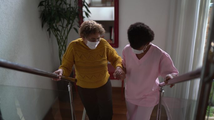 支持老年患者在家中行走或上楼的护士-佩戴防护面罩