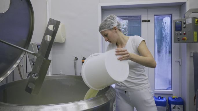 乳品厂工人将牛奶从一台机器转移到另一台机器