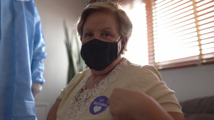 一位年长女性的肖像，展示“接种疫苗”贴纸-戴口罩