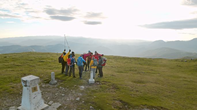 一队空中徒步旅行者在到达山顶后成功地举起了他们的登山杖
