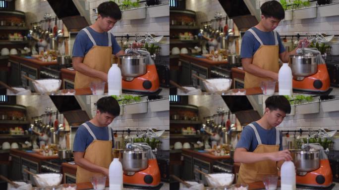 亚洲华人面包师少年男孩在厨房用立式搅拌机调整面粉