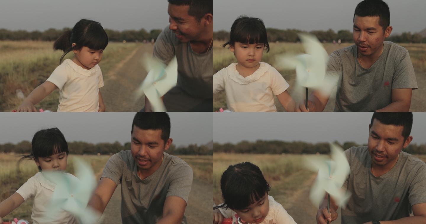 爸爸带女儿玩纸风车。
