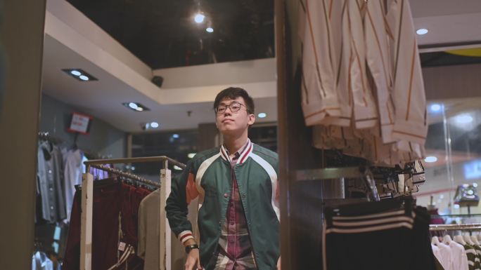 亚裔中国男性手拿男装衬衫在服装店选购