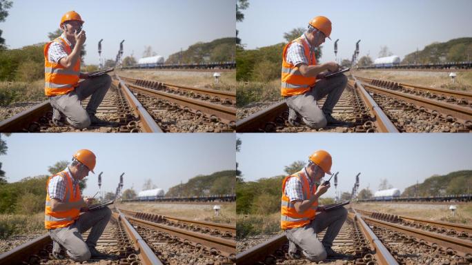 亚洲男性经理检查员检查安全铁路系统。铁路工程师穿着安全背心和头盔，维护工程师在车站检查轨道。