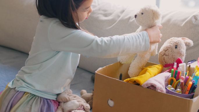 混血亚洲青年志愿者女孩整理一盒旧玩具、布、书和文具，以供捐赠，快乐慈善，亚洲社区