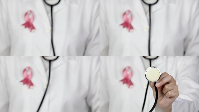 医生戴着粉色乳腺癌意识丝带，将听诊器伸向摄像机进行诊断