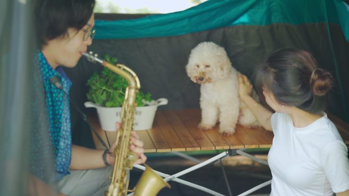 早上，亚裔中国萨克斯管演奏家和他的女朋友在露营帐篷里演奏