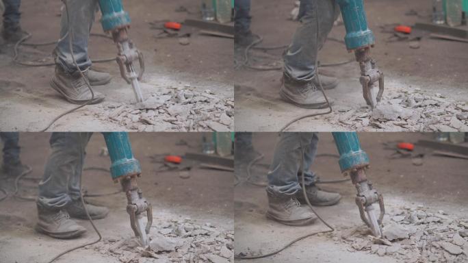 工人用手锤凿掉混凝土地板，钻混凝土地板进行维修，努力拆除工厂的建筑