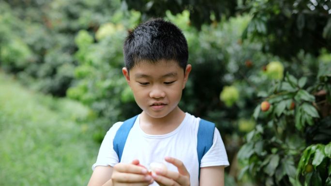 小男孩脱皮，在户外吃荔枝，竖起大拇指