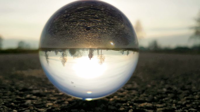 日落时分，男人走在乡间小路上——通过一个水晶球拍摄