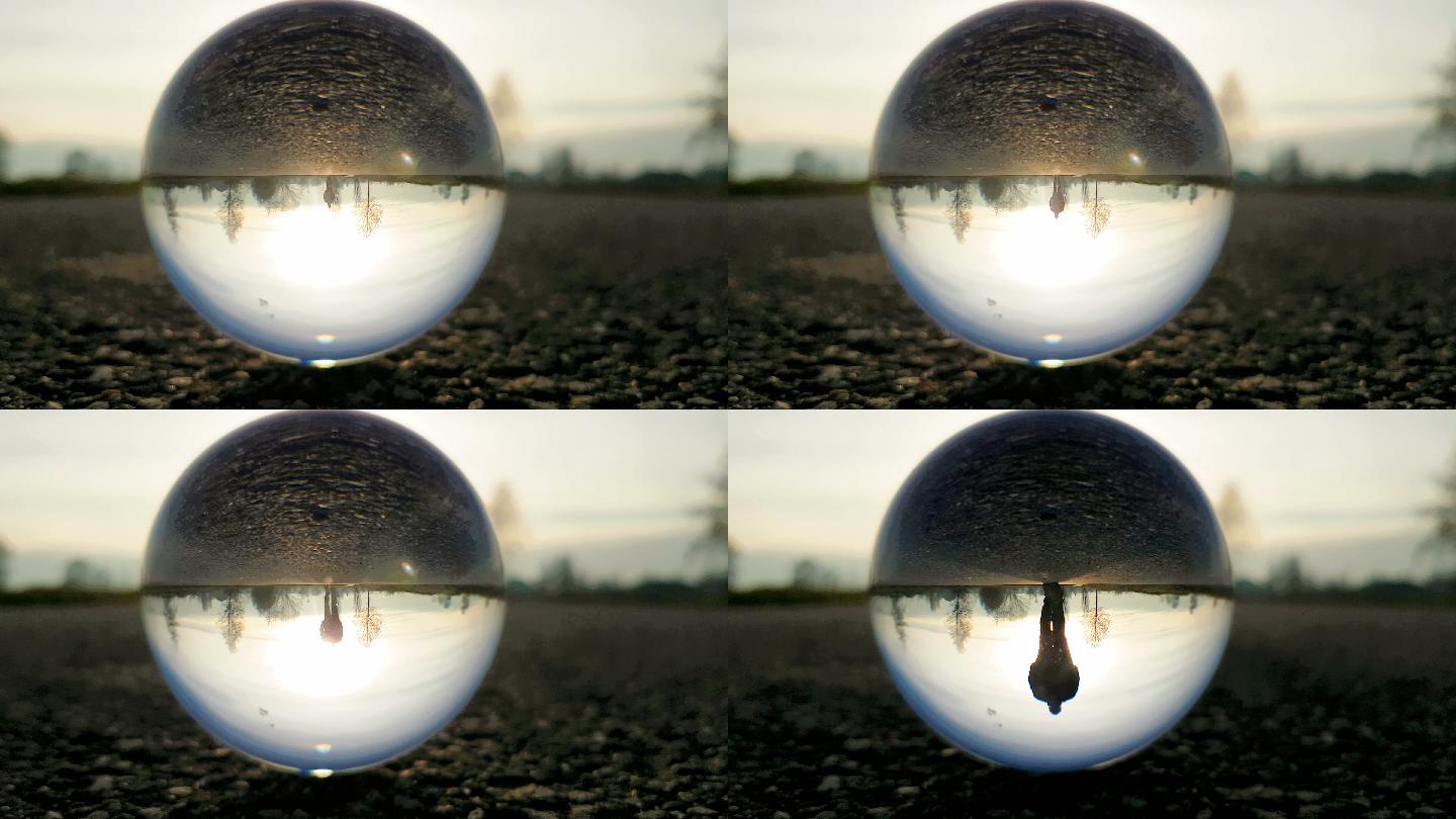 日落时分，男人走在乡间小路上——通过一个水晶球拍摄