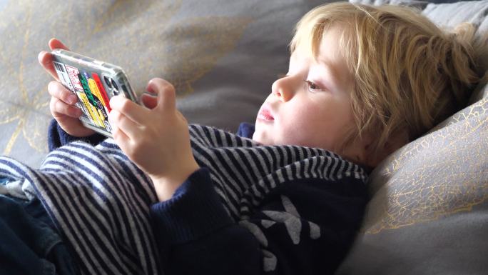 小男孩在床上使用智能手机