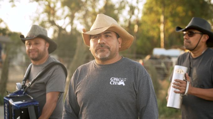 三名墨西哥移民在农场跳舞和演奏音乐