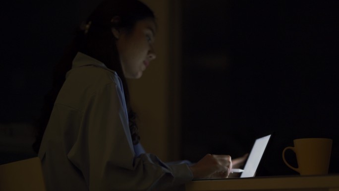 年轻的亚洲女性晚上在卧室和阳台上使用数字平板电脑。