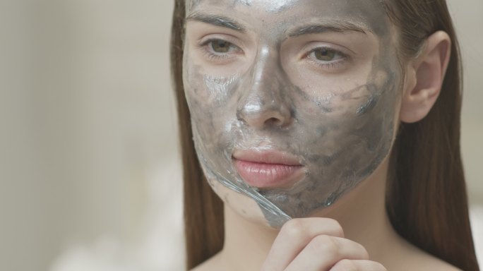特写镜头：一个女孩从脸上取下一个化妆面具。