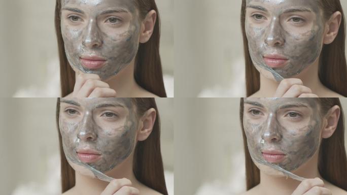 特写镜头：一个女孩从脸上取下一个化妆面具。
