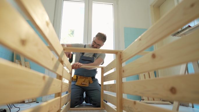 高加索木匠用电动螺丝刀连接厨房的家具