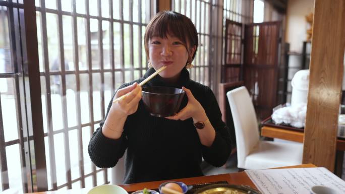 年轻女子在日本餐厅吃“Donabe Gohan”健康日本食品