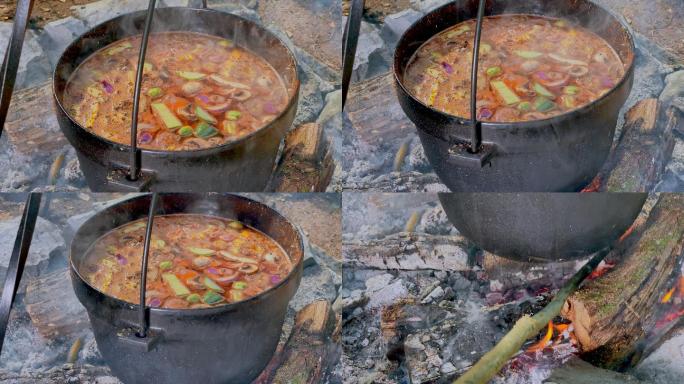 POV人员在铸铁锅中煮炖菜并照看营火