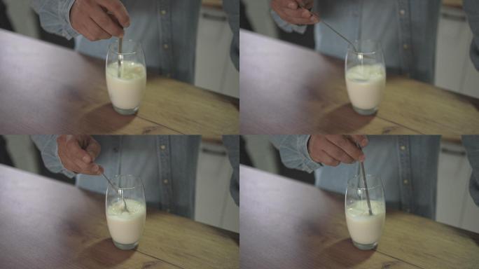 男性在厨房柜台上搅拌牛奶杯的慢动作