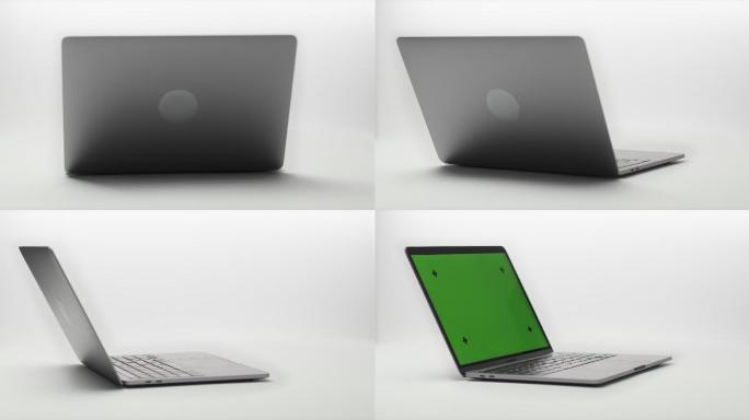 现代笔记本电脑在白色背景下绕轴旋转。笔记本电脑将显示器展开到摄像头中。笔记本电脑显示器具有绿色屏幕、