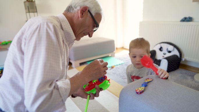 高加索祖父在家修理孙子的玩具