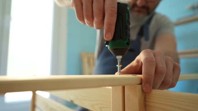 一个面目全非的木匠用电动螺丝刀把厨房里的家具连接起来
