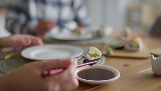 难以辨认的人用筷子吃寿司