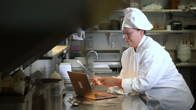 商业厨房女厨师使用笔记本电脑