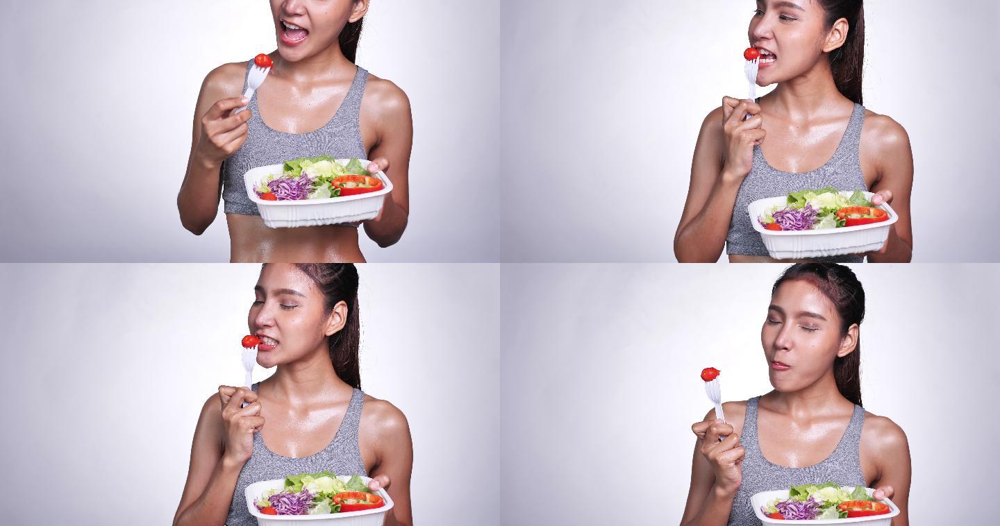 一位白人背景的年轻亚洲女性，为了美味的饮食，她吃沙拉、水果和蔬菜。