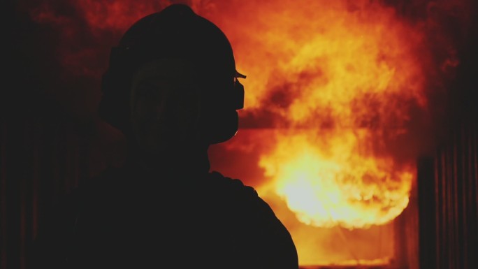 消防队员的超慢镜头消防员正走向摄像机，背景中的大火正在肆虐。