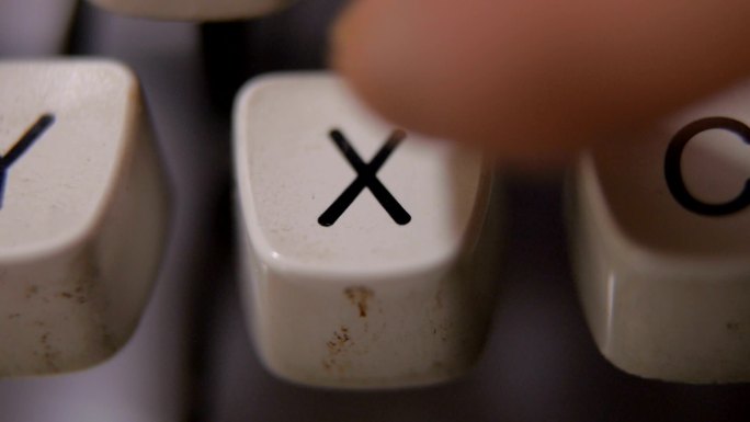 在老式复古打字机上用手指键入字母X。