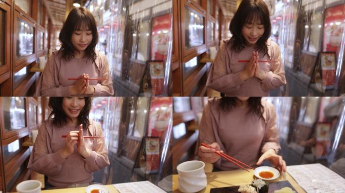女人祈祷，拿起寿司，在日本寿司餐厅吃午餐-第1部分，共3部分