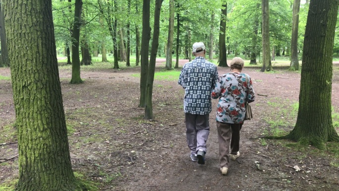公园里的老年夫妇相互搀扶老人
