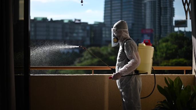 一名穿着防护服的男子喷洒房屋并消毒房屋灭虫器虫害控制病毒