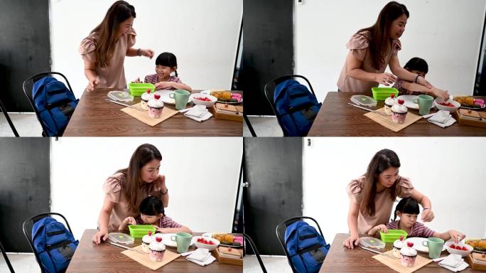亚洲母女在餐桌旁准备健康的午餐盒