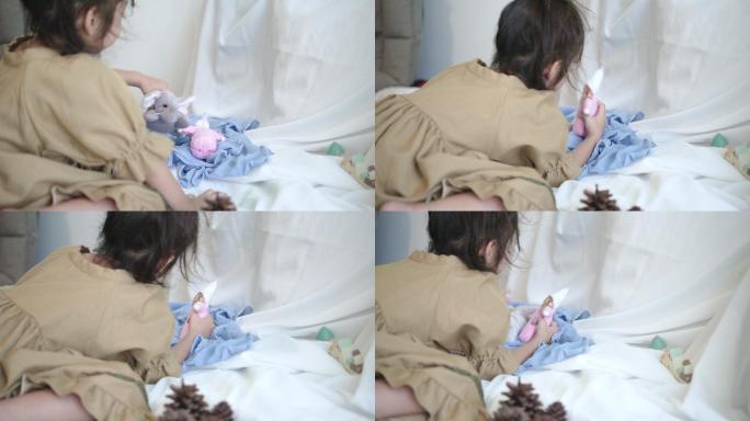 小女孩坐在沙发床上玩洋娃娃。