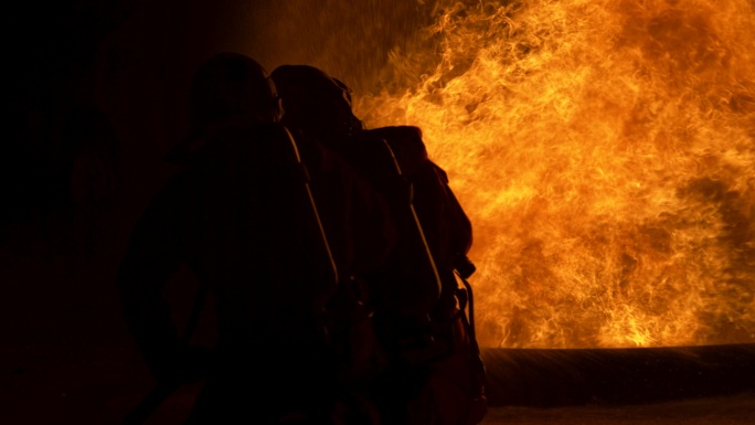 4K UHD消防队员使用旋转水雾式灭火器扑救来自油中的火焰，以控制火势不蔓延。消防员和工业安全概念。