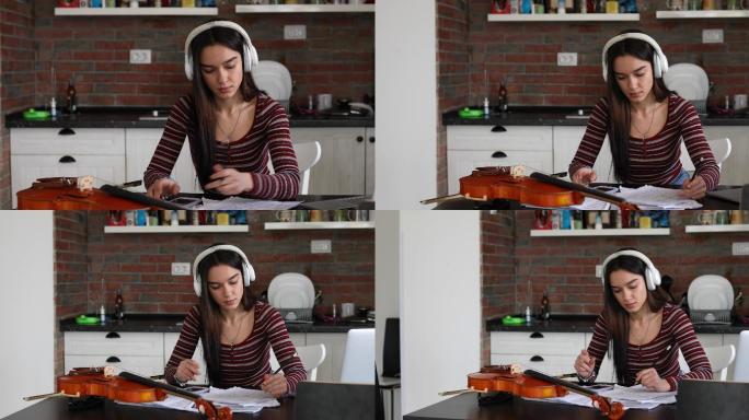 一位年轻而有才华的音乐学校女生在在线小提琴课上使用耳机。