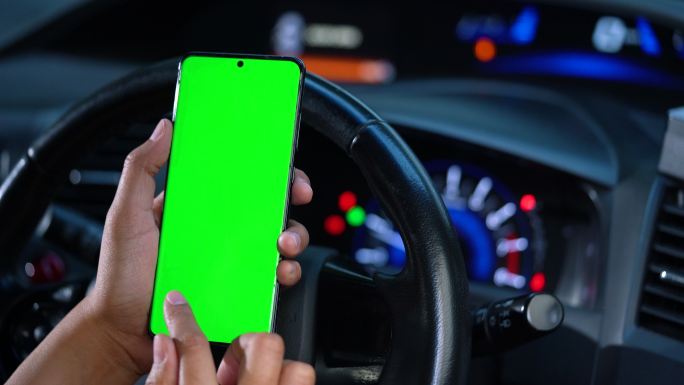 在电动汽车中，女性手持一部带有绿色空白屏幕的智能手机，用于指示、按摩、定位和商务。女性坐在现代电动汽