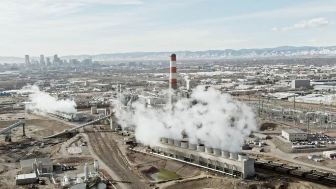 晴朗的一天，科罗拉多州一座发电厂的蒸汽从落基山脉和丹佛市中心升起的空中无人机拍摄