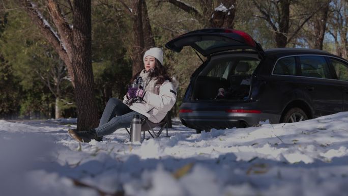 青年女人坐在雪地里喝热水