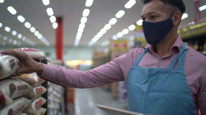 成年男子戴口罩用数码平板电脑控制超市库存