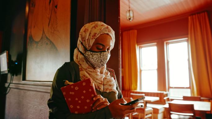 一名年轻女子在咖啡馆拿书时使用手机的4k视频片段