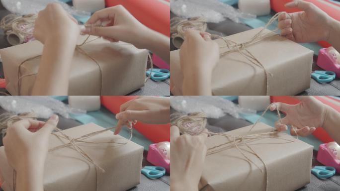 俯视亚洲少女制作手工物品护理包。可爱的女孩正在打包一个腰带盒，准备从远处寄给她的家人或朋友。