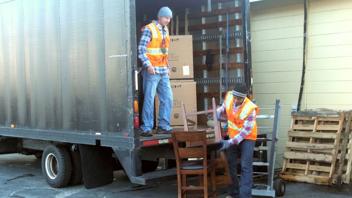 两名工人将家具装载到送货车上