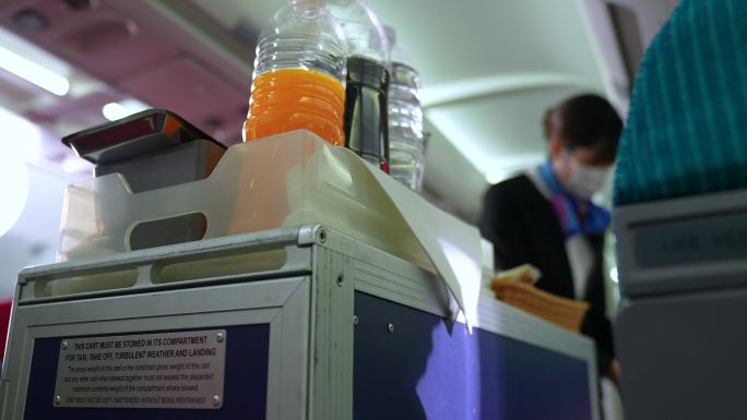 带口罩的空姐为乘客提供食物。从乘客看着空姐的角度拍摄视频。