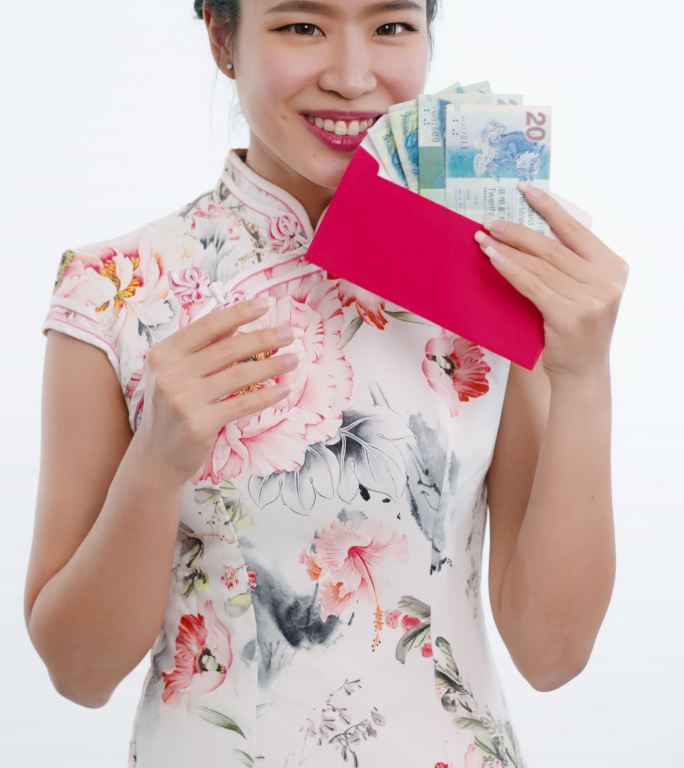 肖像：穿着旗袍白色花卉图案连衣裙的中国/亚洲女性将钞票递成红色，送给她的家人、亲戚和朋友，以庆祝新年