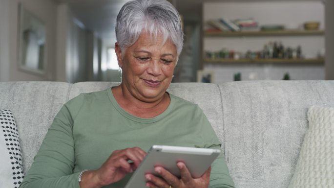 一位成年女性在家沙发上休息时使用数字平板电脑的4k视频片段