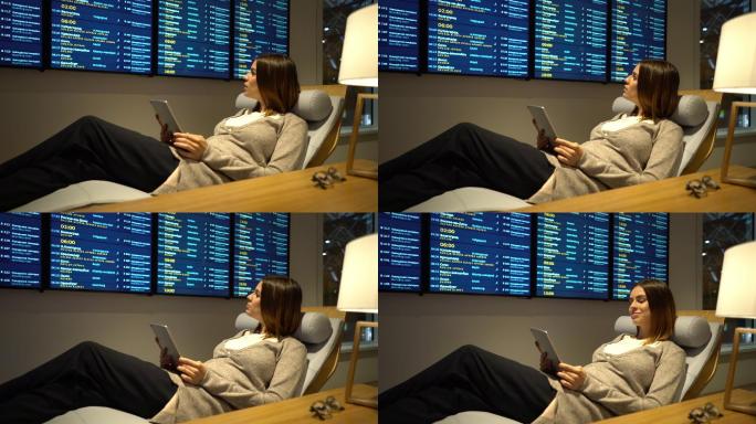 孕妇在机场贵宾休息室使用平板电脑休息，查看航班时刻表